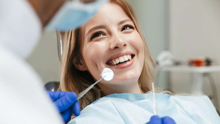 woman smiling in dentist exam chair | dental cleanings oakbrook terrace